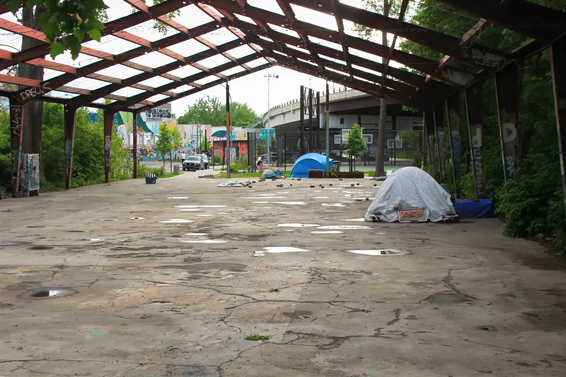 Deux tentes dispersées sur la surface de béton et la structure servant à soutenir un toit de l'Entrepôt 77.