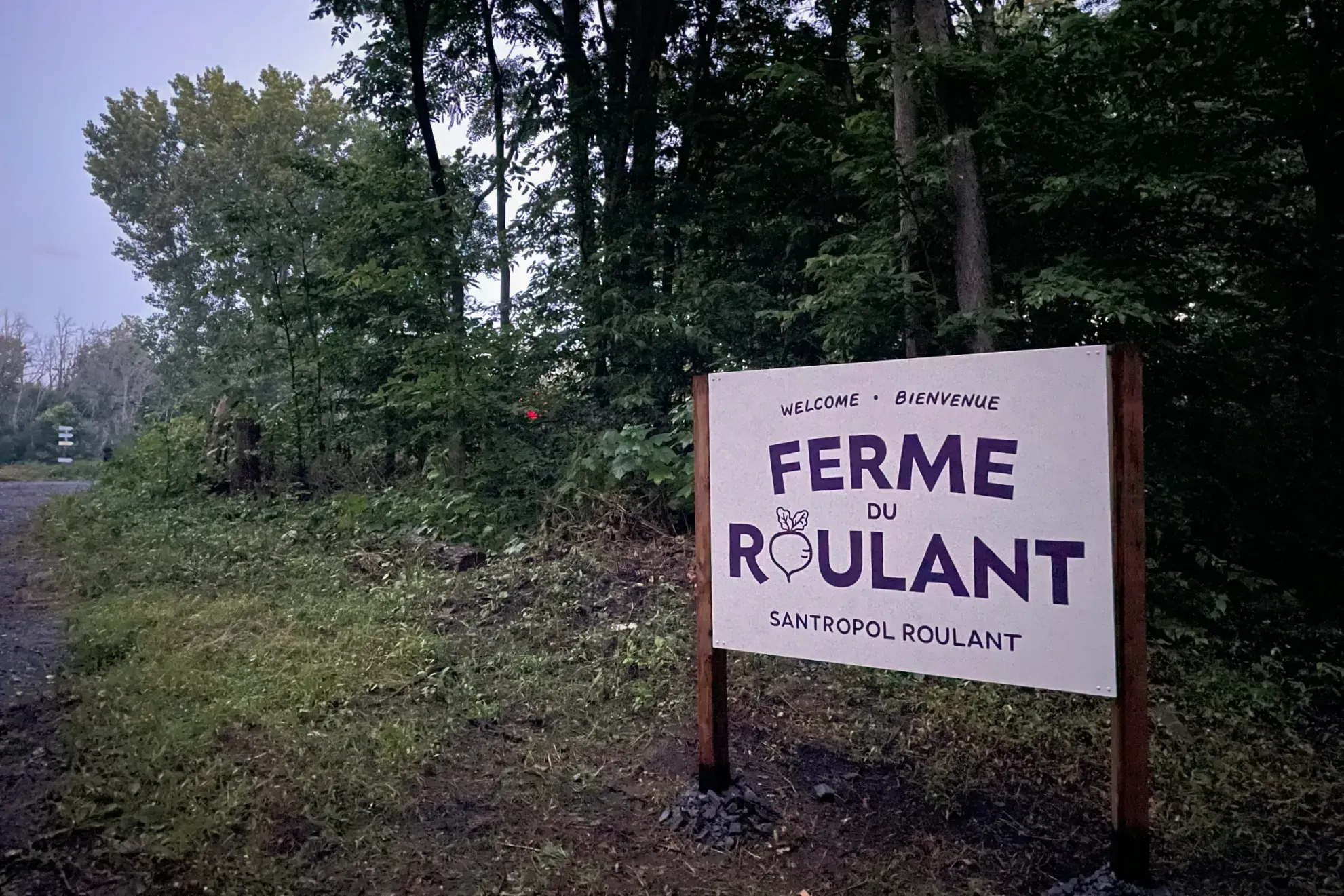 Un pancarte affiche le message «Bienvenue – Fermme du Roulant – Santropol Roulant». 