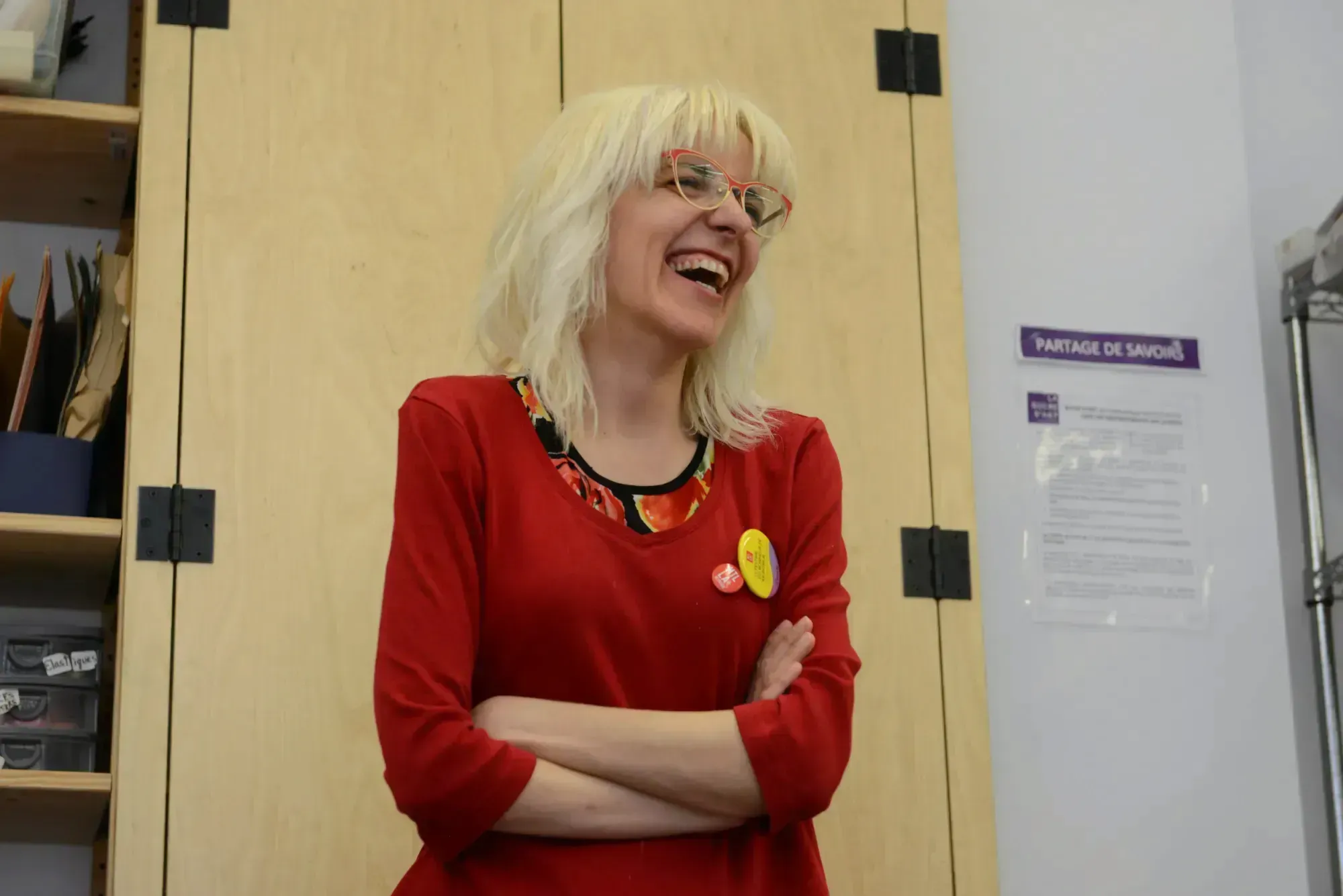 Rossana Bruzzone souriante et vêtue de rouge, accotée sur une armoire de la bibliothèque Mordecai-Richler.