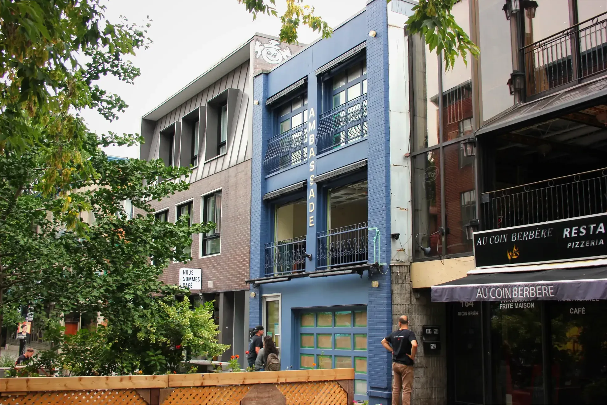 Vue de biais sur l'immeuble recouvert de bleu qui accueillera l'Ambassade. Il est entourré de Nous sommes café et du restaurant Au coin berbère.
