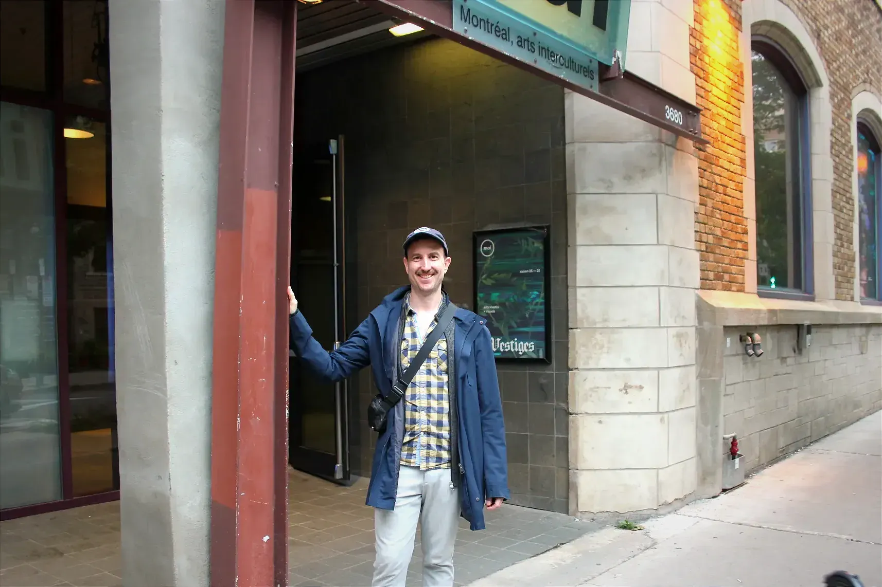 Olivier Sylvestre pose sous l'enseigne «MAI» à l'entrée de Montréal, arts interculturels.