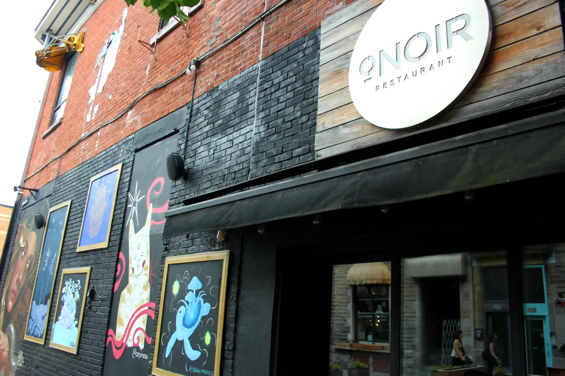 La façade du restaurant Onoir, qui comprend quelques œuvres d'art ainsi qu'une vitre qui ne fait que réfléchir la lumière.