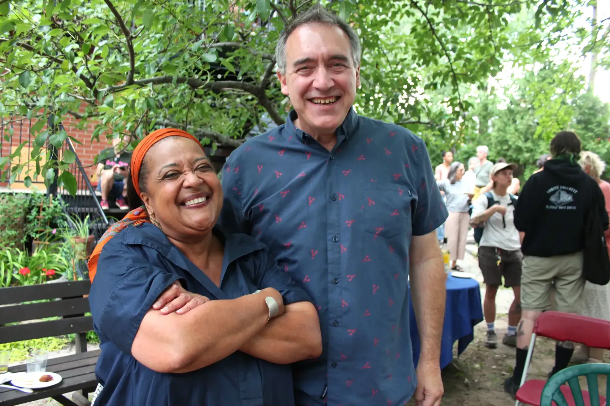 Marie Sterlin et Alex Norris sourient à la caméra, parmie les fêtards réunis dans le cour de la coop Marie-Anne.