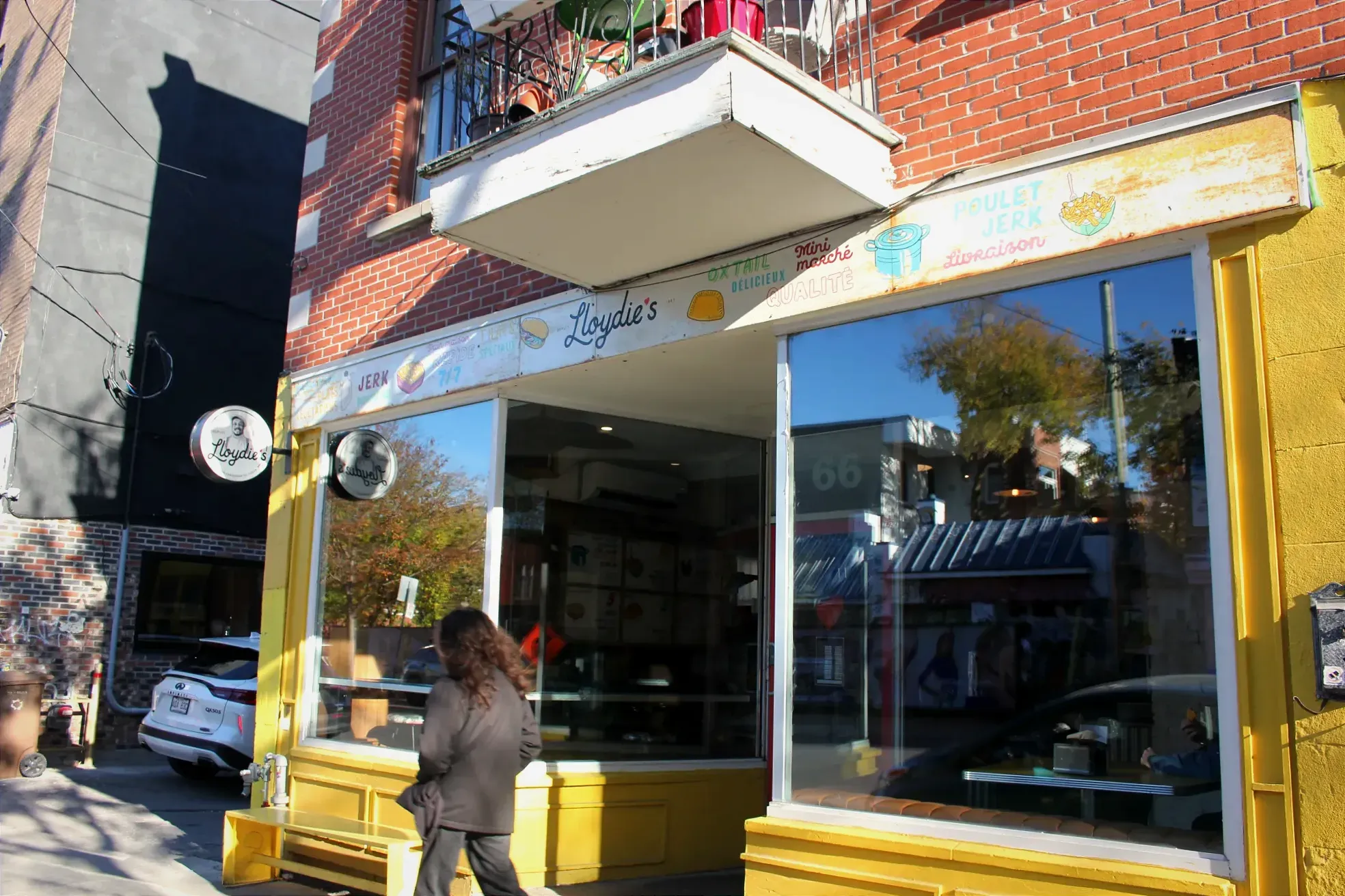 Un passant se dirige vers le côté gauche du cadre, passant devant la façade jaune de Lloydie's.