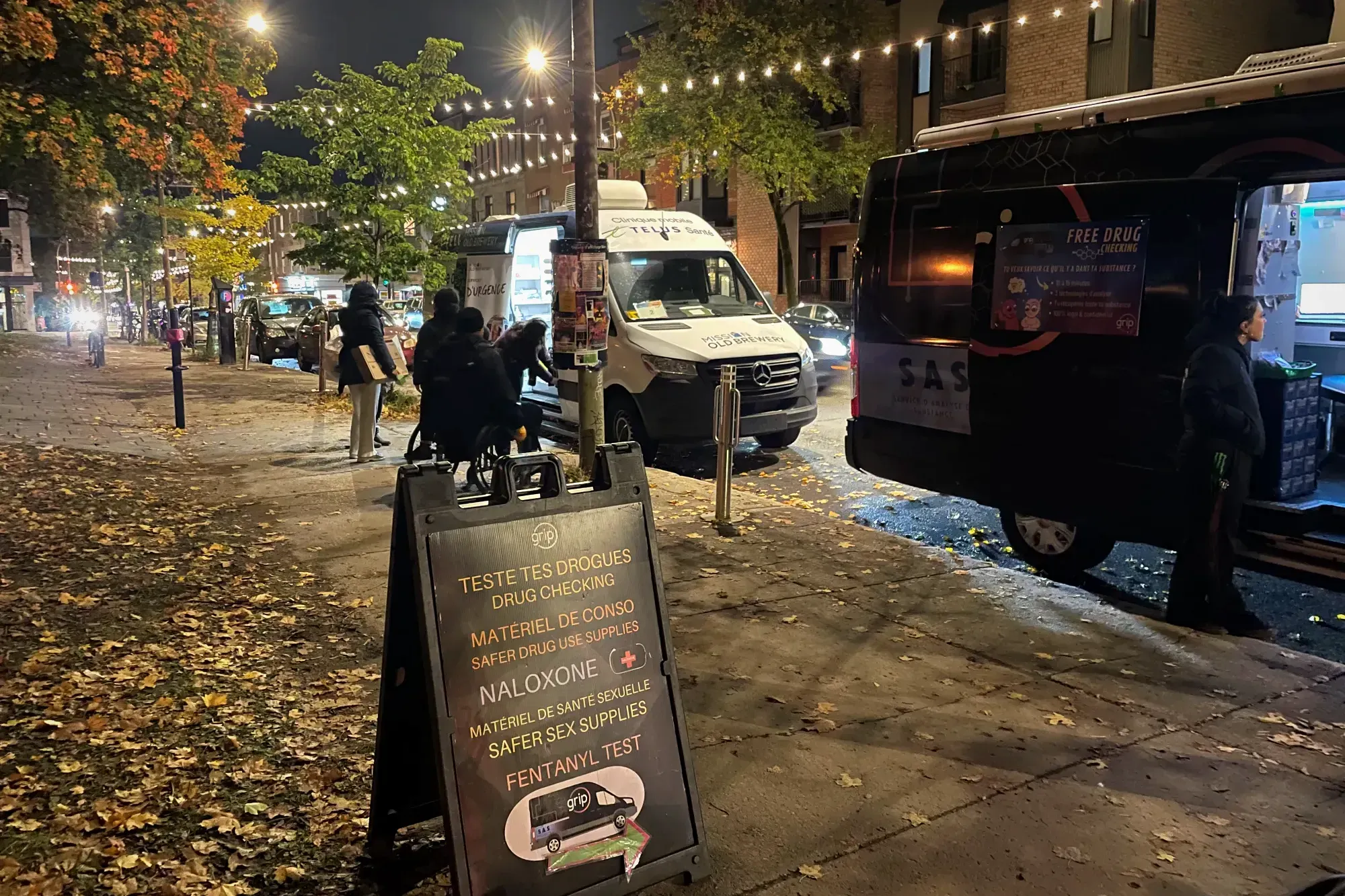 «Teste tes drogues», peut-on lire sur une pancarte placée sur le trottoir, à proximité de la fourgonnette du GRIP. La clinique mobile de la Mission Old Brewery Mission est visible en arrière-plan. 