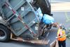 Une éboueuse lance un sac de recyclage à l'arrière d'un camion de poubelles.