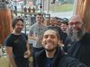 Six personnes posent devant des cuves de brassage.