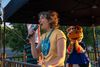 Marianne Giguère en été, micropone à la main, sous un chapiteau, au coucher du soleil.