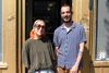 Les deux intervenants posent devant la porte, les yeux plissés en réaction à la lumière du soleil.