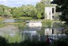 On voit la fontaine au milieu du bassin, avec quelques passants devant et le théâtre de Verdure derrière. 