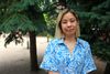 Mme Wong pose devant quelques conifères dans un petit parc du Plateau-Mont-Royal.