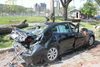 Une voiture a été écrasée par un arbre. On voit la carrosserie endommagée et les vitres cassées.