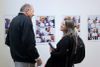 Des pages du photo-roman sont exposées sur les murs, alors que deux personnes discutent devant elles.