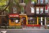 On voit le restaurant recouvert de brique jaune, en été, à partir du côté opposé de l'avenue. 