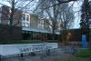 Vue de l'entrée de l'école Saint-Enfant-Jésus sur la rue Villeneuve. On peut lire «ECOLE ELEMENTAIRE» sur un imposant panneau en béton en avant-plan.