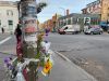 Des fleurs collés sur un poteau en premier plan, avec l'avenue du Parc et plusieurs véhicules en arrière plan.