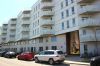 La façade blanche de la Coop MIL, vue du côté opposé de la rue. Les balcons des différents appartements ressortent comme des vagues angulaires de la surface.