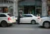 L'homme tend la main vers la vitre d'une automobile, alors qu'il se trouve entre deux voies de circulations occupées. 