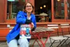 Mme Escabasse pose avec son livre à une table installée à l'extérieur du Dépanneur café, dans le Mile End. 