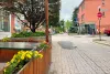 L'avenue Duluth est tranquille sous la grisaille. Une terrasse fleurie déborde du cadre, à gauche. On voit une ambulance au loin.
