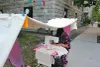 L'artiste utilise une machine à coudre placée sur une petite table rose, sur le côté d'un trottoir du Plateau.