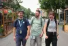 Les trois intervenants marchent vers la caméra en souriant, sur l'avenue piétonne. 