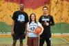 Les trois posent dans le gymnase de l'école Jeanna-Mance. Mme Ghazal porte un dossard des Dragons et tient un ballon de basket dans ses mains.