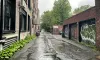 La ruelle sous la pluie, avec trois portes de garage, à droite, recouvertes de graffitis.