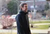 Steven Guilbeault, vu de côté semble sourire en direction d'une porte d'entrée de maison que l'on devine à l'extérieur du cadre, à droite.