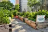 Plusieurs grands bacs en bois remplis de végétaux sont installés sur la rue, avec un corridor qui les séparent. Une pancarte annonce le nom des Jardins du Monde & des Premières Nations.