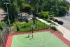 Un jeune adolescent, vu de haut, pratique ses lancers au panier. À quelques mètres du terrain de basketball se trouvent des tentes.