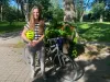 Justine McIntyre pose devant un vélo, dans un parc, sous le soleil.