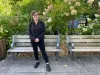 Roxane Milot, habillée en noir, pose devant un banc public, près d'un parc.