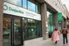 Deux piétons, vus de dos, dépassent l'entrée de la Caisse Portugaise Desjardins, au 4244, boulevard Saint-Laurent.