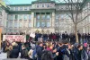 Une foule devant le bâtiment avec une banderole, Notre école n'est pas à vendre.
