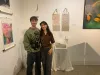 Un homme et une femme posent en souriant l'un près de l'autre dans une salle où se trouvent des œuvres d'art.