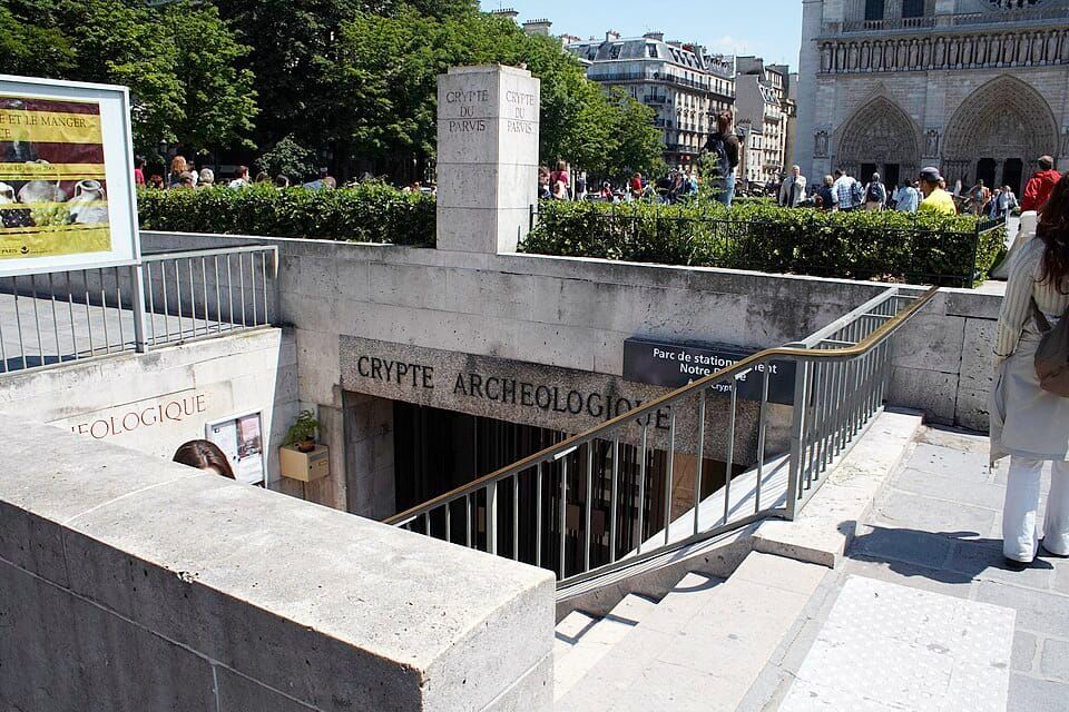 Entrance staircase to the Crypte Archéologique on the Île de la Cité in Paris, with the sign visible. Kurt Raschke / Wikimedia Commons / CC BY 2.0,  above the underground museum entrance