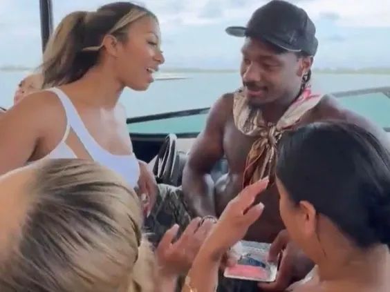 Stefon Diggs on a boat with a group of women holding a bag of a pink substance
