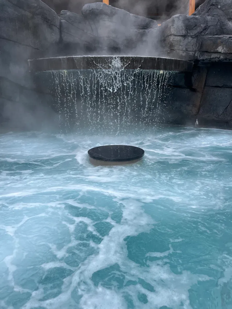 Outdoor thermal pools at Hotel Canoe Banff with mountain views and fire pit glowing