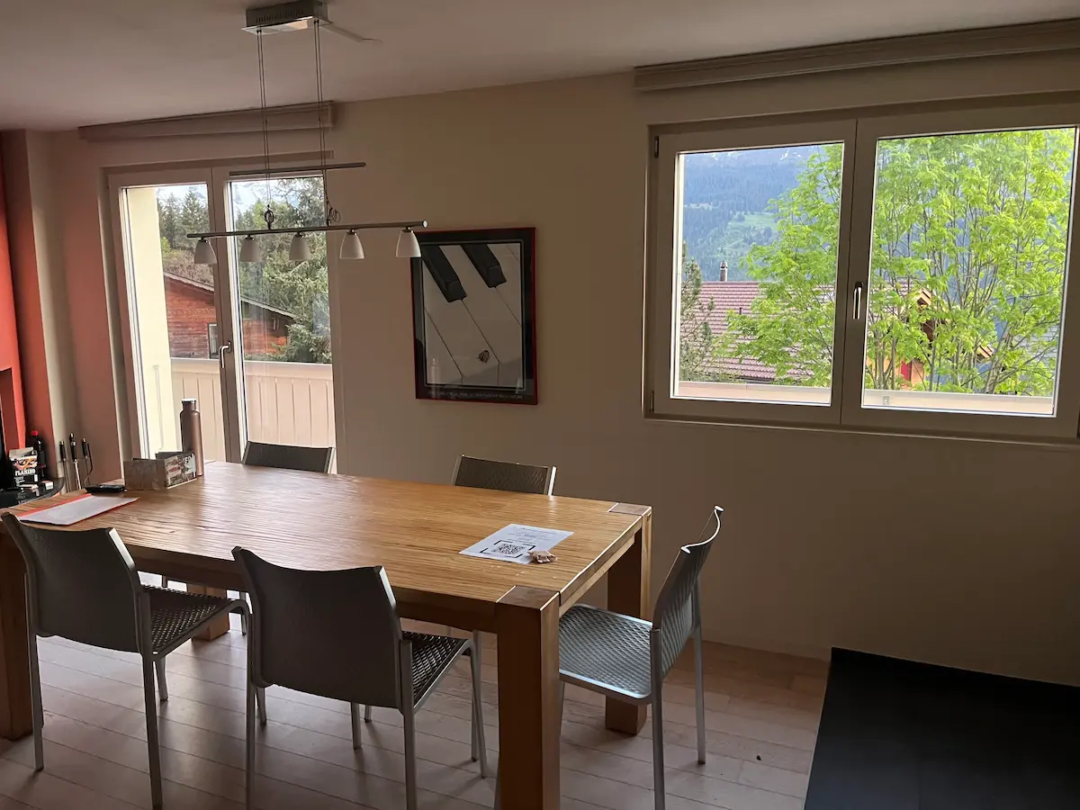Wengen apartment dining room with large window and mountain view, multi-generational family self-catering Switzerland