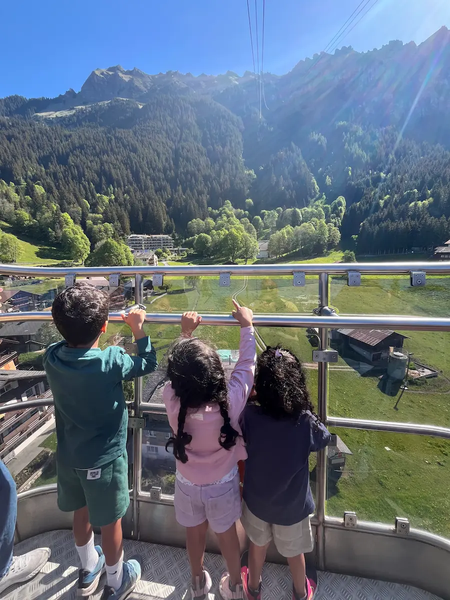 Open cable car Royal Carriage ascending from Wengen to Männlichen with snow-capped Swiss Alps behind, Jungfrau Region Switzerland family travel