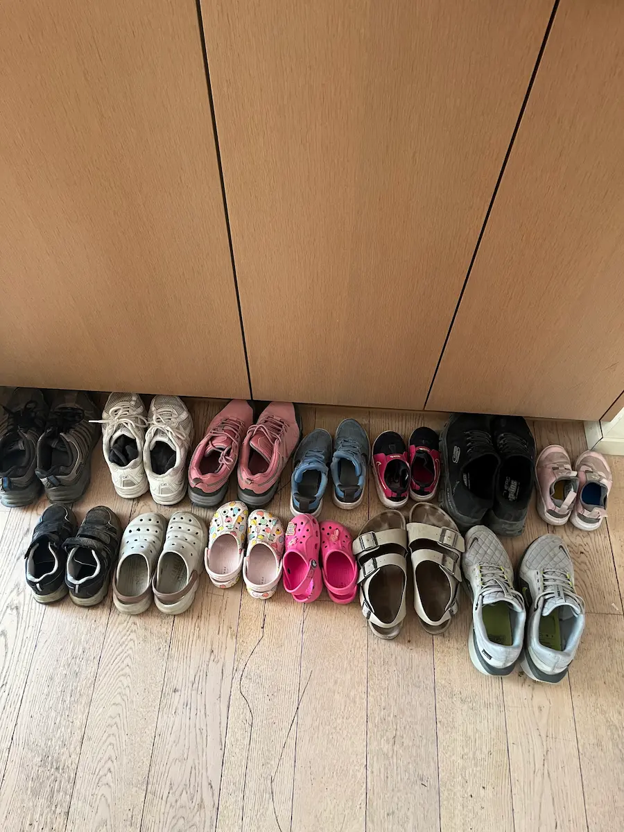 Family hiking boots lined up on floor, self-catering Wengen apartment Switzerland multi-generational family travel preparation