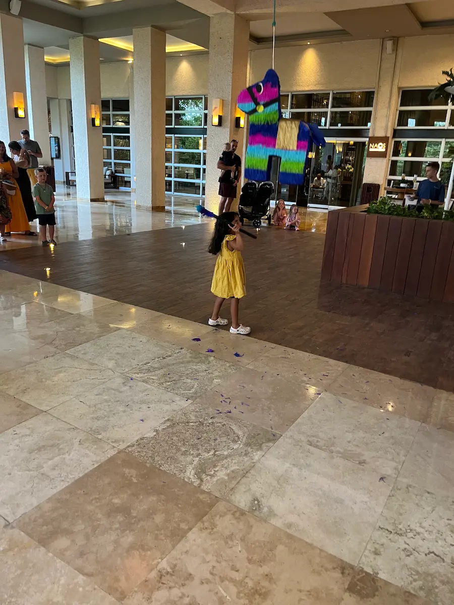 small girl hitting colourful piata