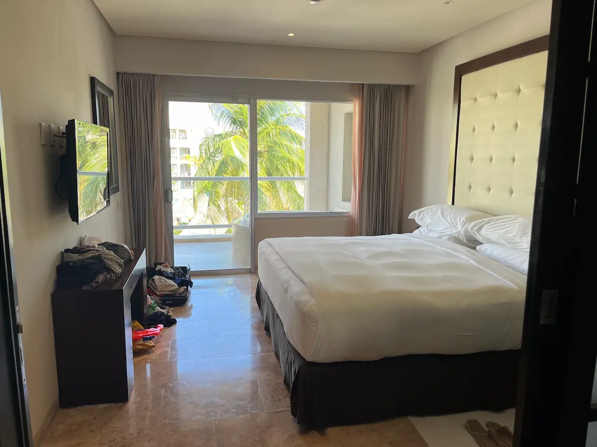 King bed in a Master Suite bedroom at Paradisus Playa del Carmen, balcony and palm trees visible through open doors.