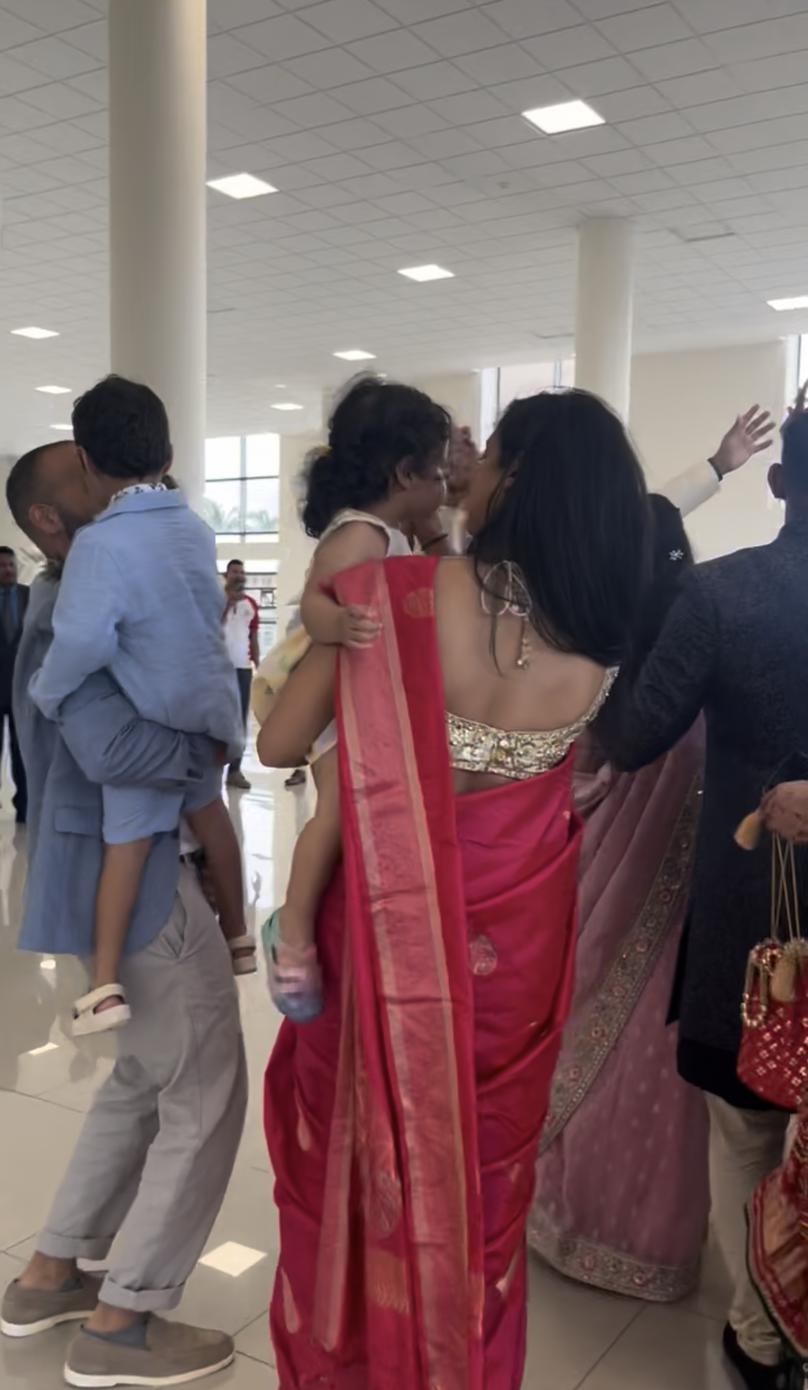 Family group arriving at a Mauritius wedding venue, adults carrying young children dressed for the celebrations.