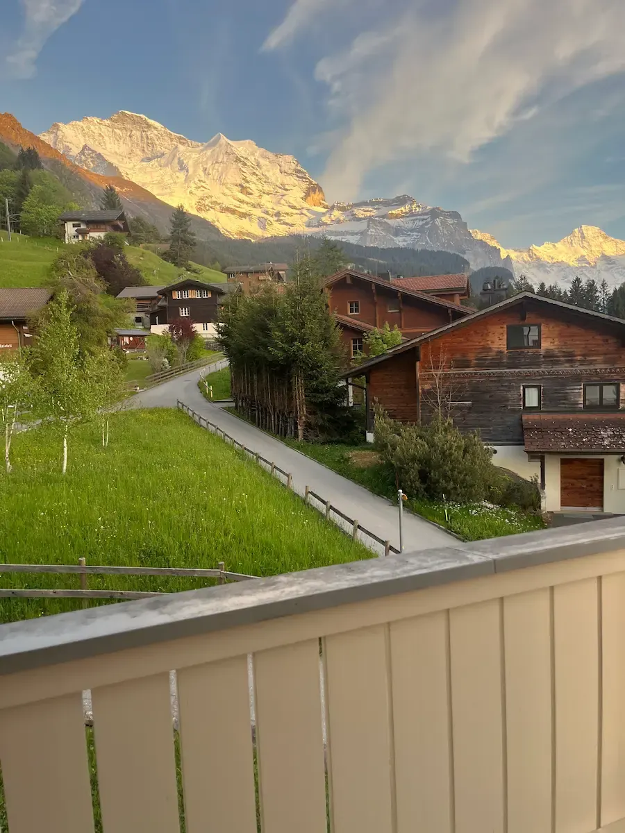 Wengen apartment balcony with wooden table and snow-capped Jungfrau mountain view, multi-generational family Switzerland accommodation