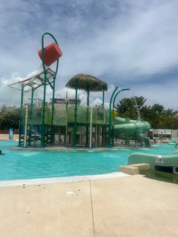 Main pool at the Paradisus Playa del Carmen aqua park, slides and loungers visible, palm trees surrounding.