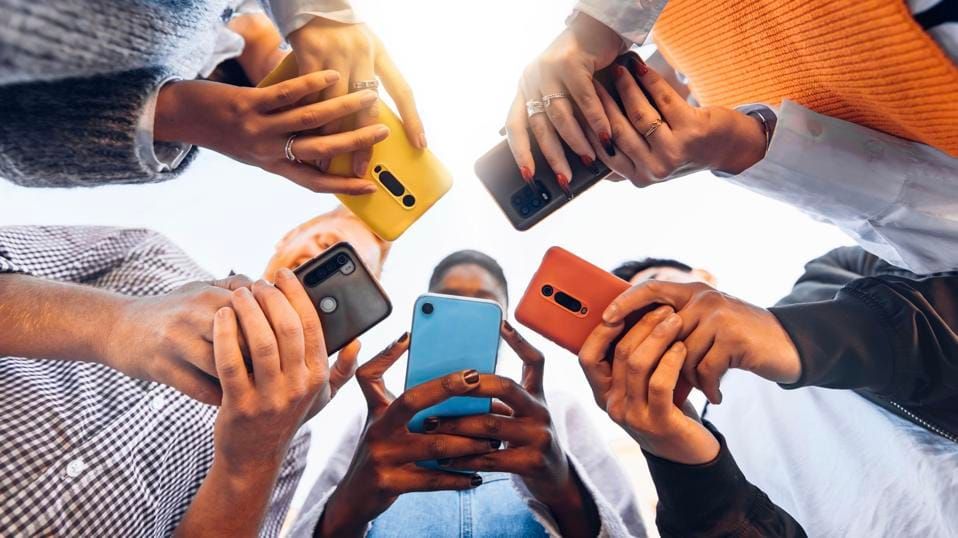 Teens in circle holding smartphones.
