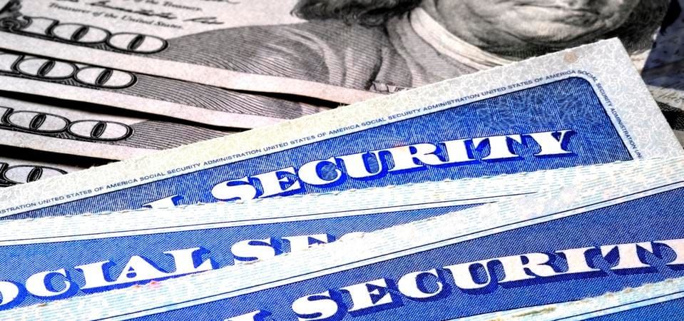 Social Security Cards in a Row over hundred-dollar bills.