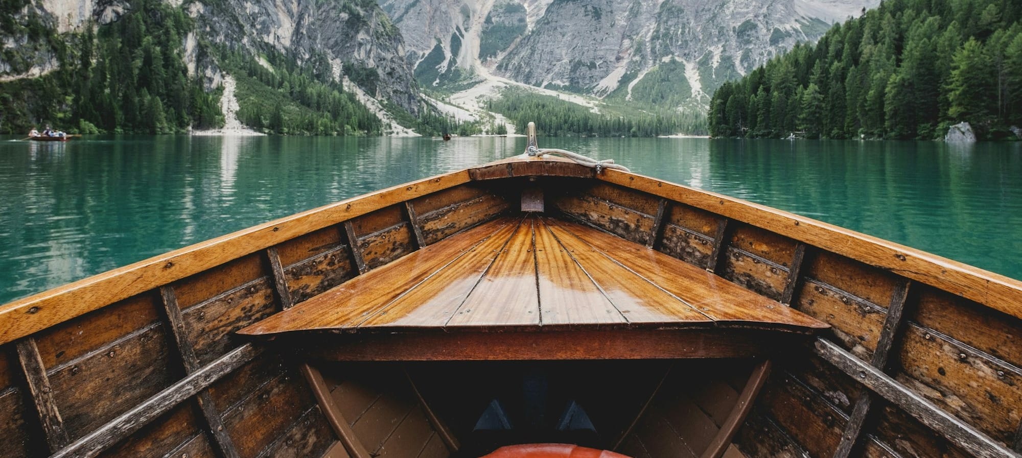 brown wooden boat moving towards the mountain